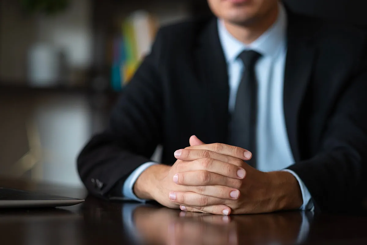Lawyer sitting behind a desk with his hands clasped together