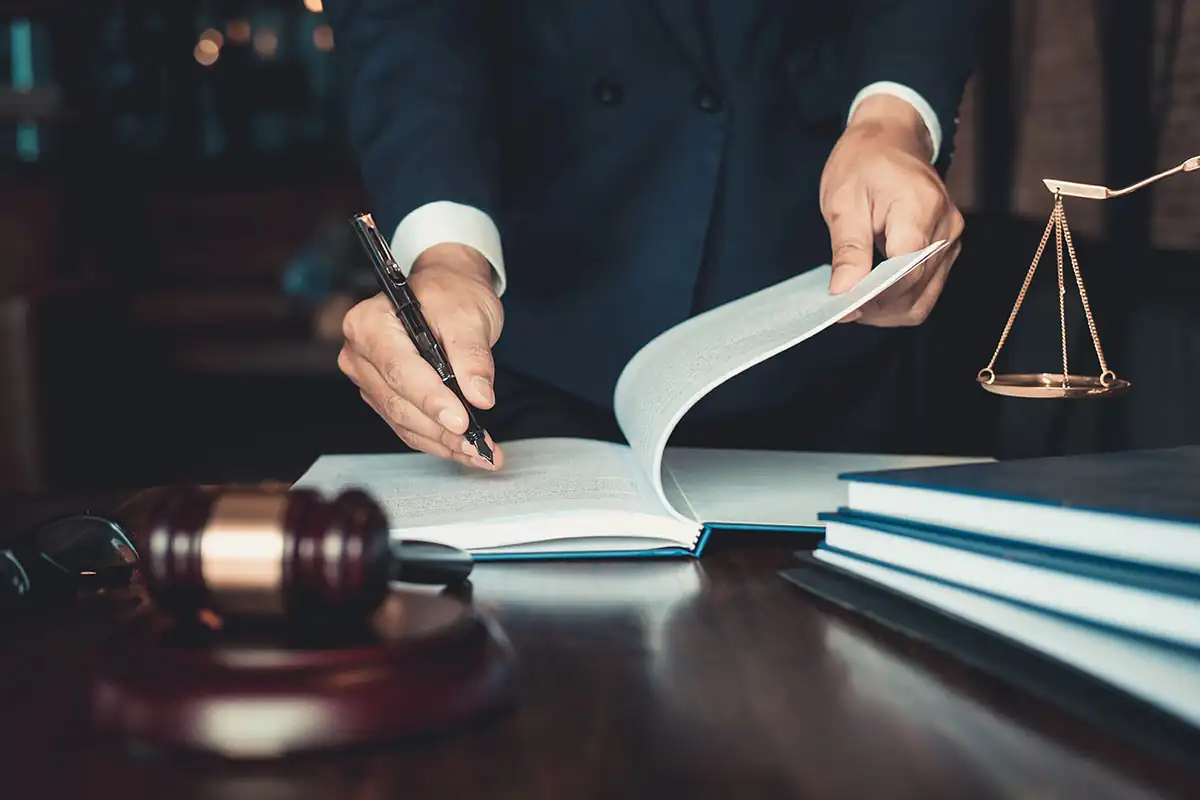 Lawyer standing behind a desk signing a book